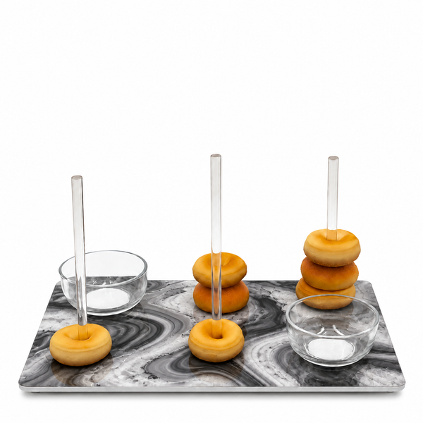 A marble donut stand with three vertical clear glass rods holding donuts, alongside two small clear glass bowls, all arranged on a white background.