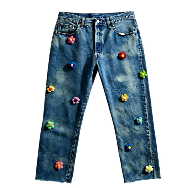 Blue jeans with colorful flower patches on a white background