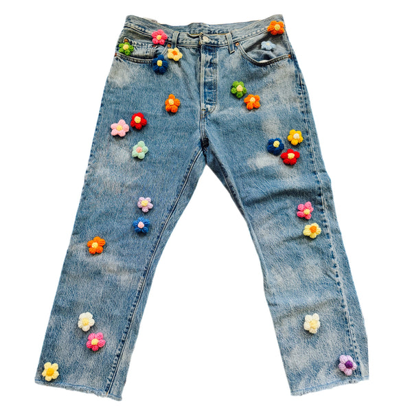 Blue jeans with colorful flowers attached on a white background