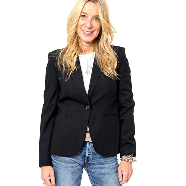 Woman wearing a classic black blazer with a white top and blue jeans.