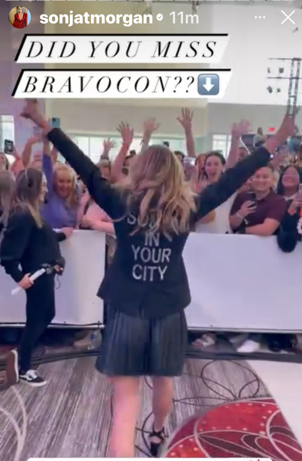 Woman wearing a custom black blazer with Sonja in Your City lettering on the back.