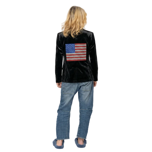 Person wearing a black jacket with an American flag patch on the back, standing against a white background.