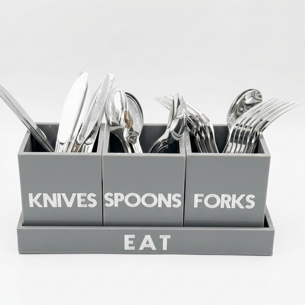A gray cutlery organizer with three compartments labeled 'KNIVES', 'SPOONS', and 'FORKS' above a base labeled 'EAT', shown holding silver flatware on a white background.