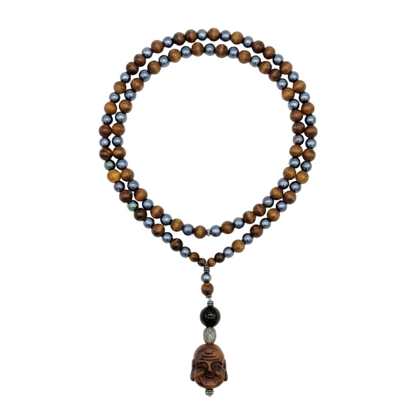 A double-strand beaded necklace featuring brown tiger's eye beads and dark blue-gray freshwater pearl beads, with a carved wooden Buddha pendant hanging from a silver-toned chain, displayed on a clean white background.