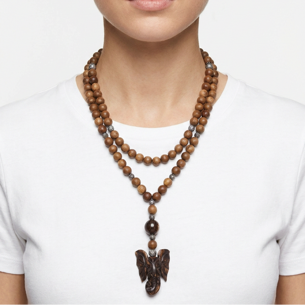 A model wearing a double-strand wooden bead necklace with a carved dark brown bird pendant, styled with a white t-shirt against a light gray background.