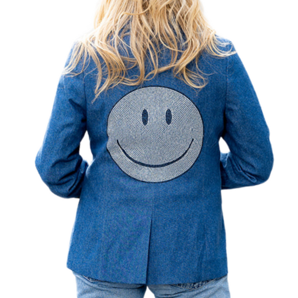 Close-up back view of a woman wearing a blue denim blazer with a large silver rhinestone smiley face.