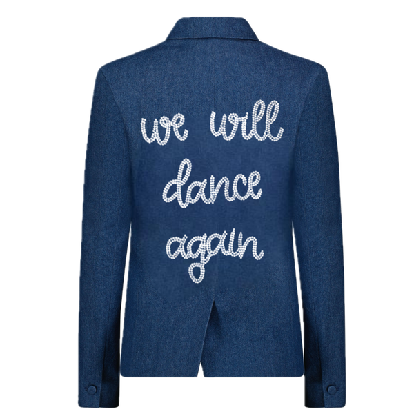 Back view of a blue denim blazer with silver rhinestone we will dance again lettering.